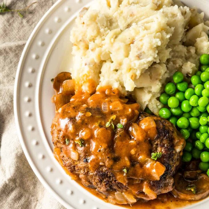 paula deen salisbury steaks with green peas and mashed potatoes on the plate
