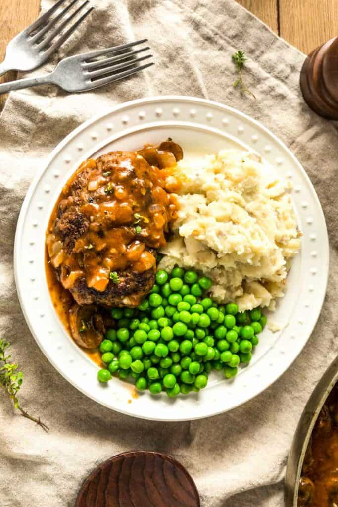 paula deen salisbury steaks with green peas and mashed potatoes on the plate